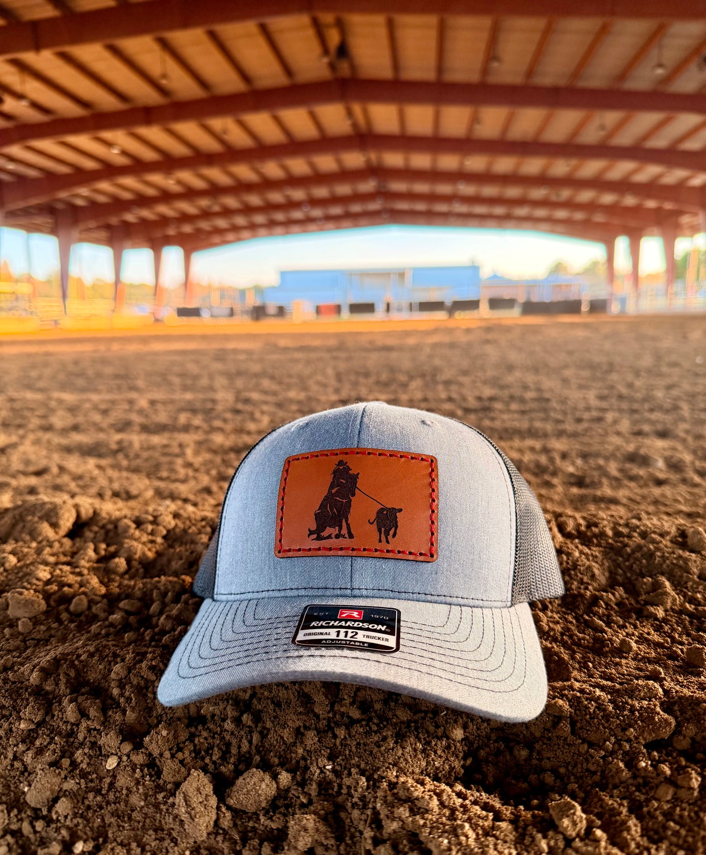 Gray cap with brown leather patch on a dirt field with a breakaway roper design