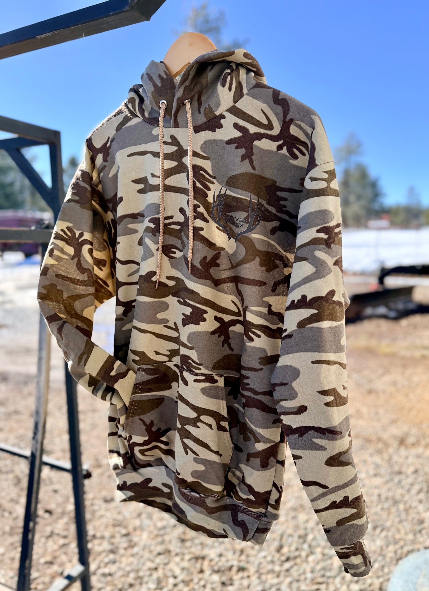 camouflage hoodie on a hanger with a blurred outdoor background