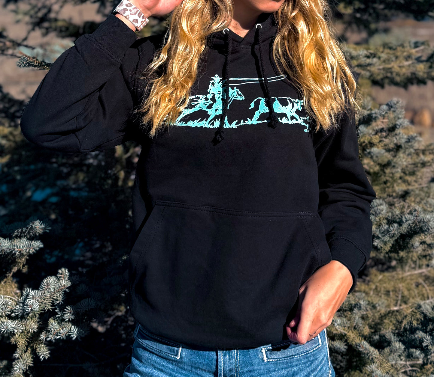 Person wearing a black hoodie with a graphic design outdoors
