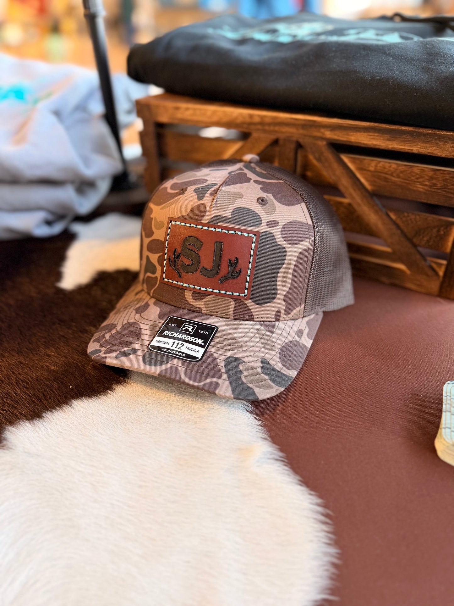 Brown Duck Camouflage baseball cap with custom branded leather patch and Richardson logo with a wooden background.