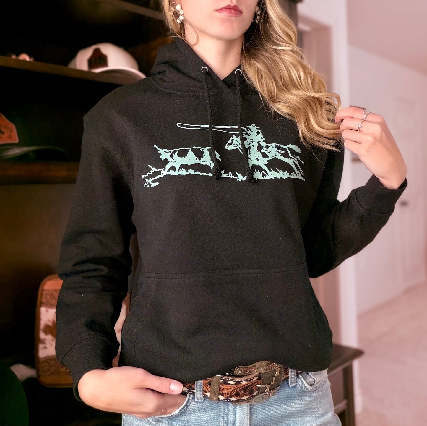 Person wearing a black hoodie with white graphic design, standing indoors.