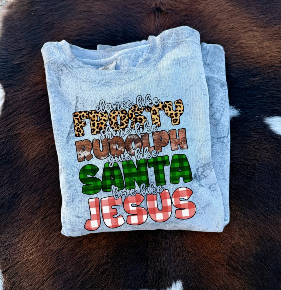 folded Gray marbled sweatshirt with colorful text design on "Frosty, Rudolph, Santa, Jesus"