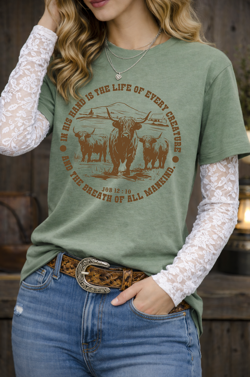 Person wearing a green t-shirt with a graphic design, white lace sleeves, and blue jeans.
