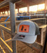 Gray cap with leather patch featuring a breakaway roping design, placed on metal bars with a barn background.