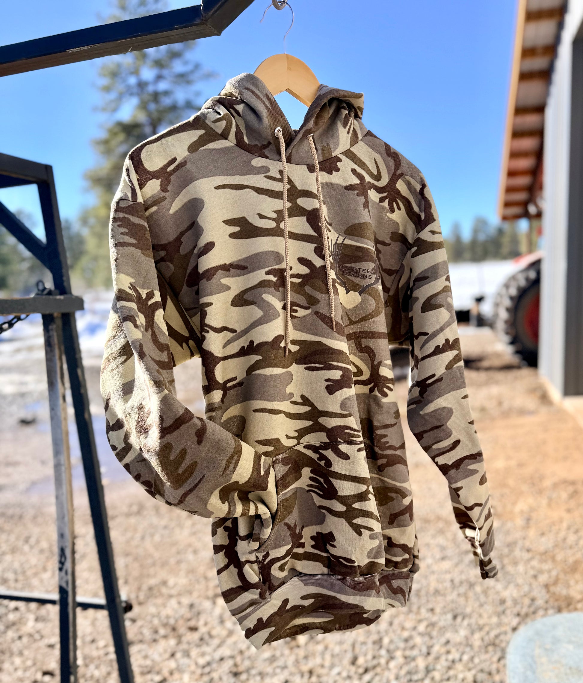 Camouflage hoodie on a hanger with a blurred outdoor background