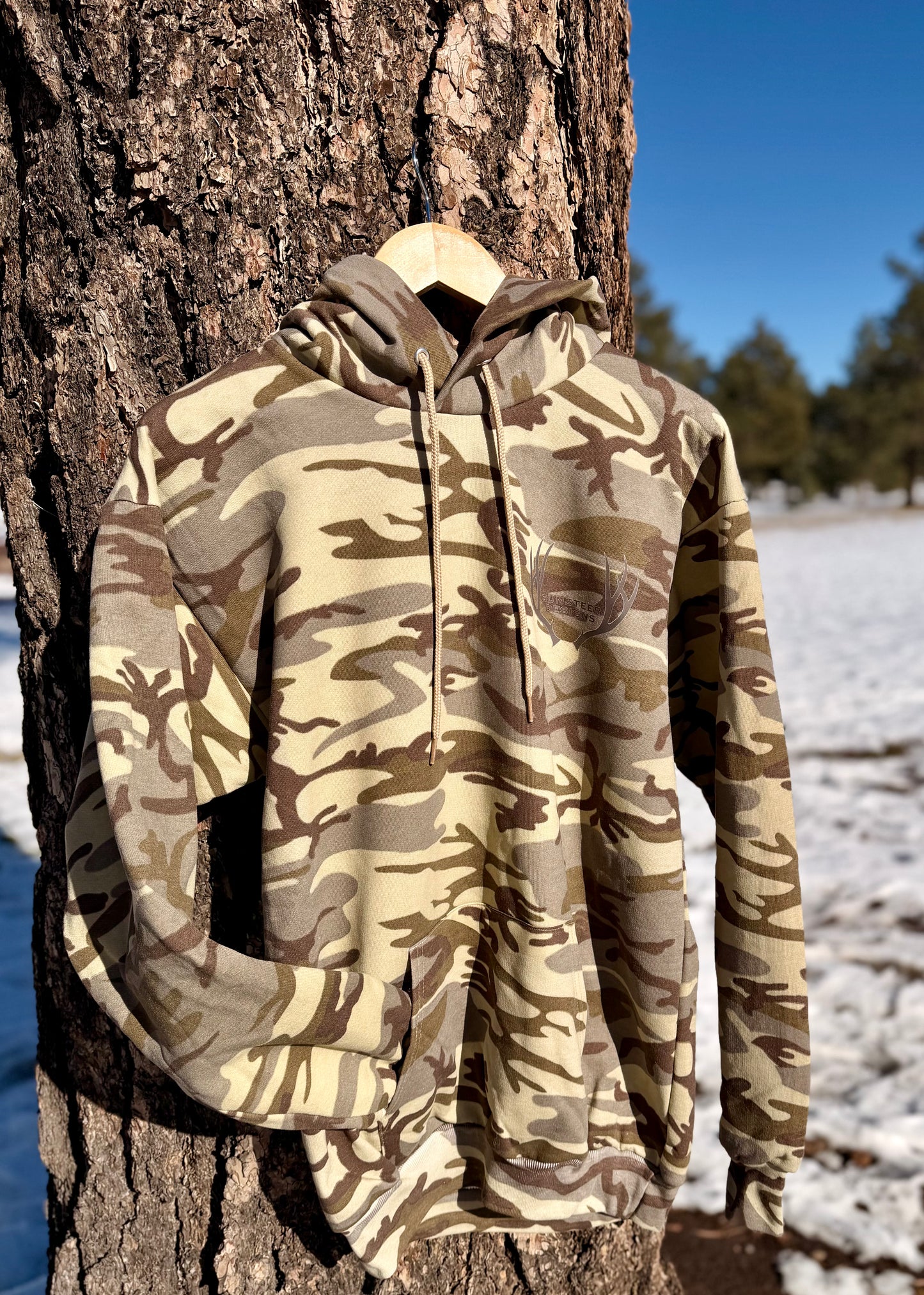 Camouflage hoodie hanging on a tree in a snowy forest