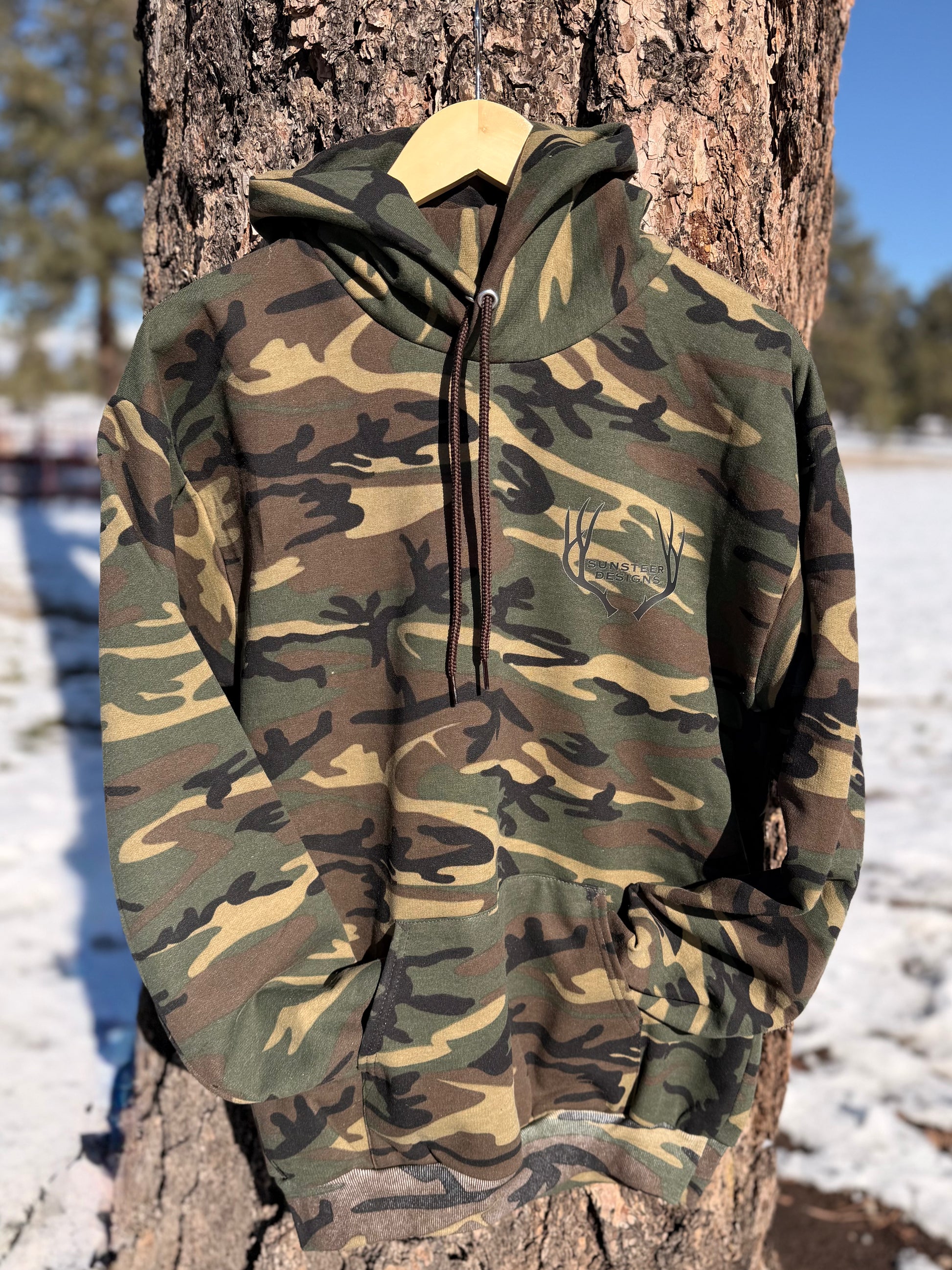 Camouflage hoodie hanging on a tree in a snowy landscape
