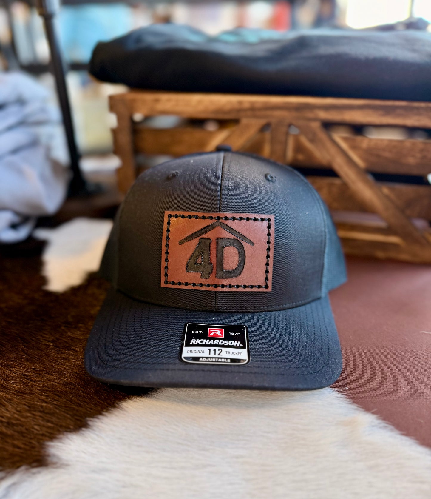 Black cap with a branded brown leather patch featuring the number 4D on a fur surface.