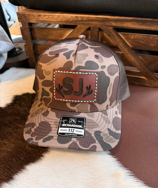 Brown Duck Camouflage baseball cap with custom branded leather patch and Richardson logo with a wooden background.