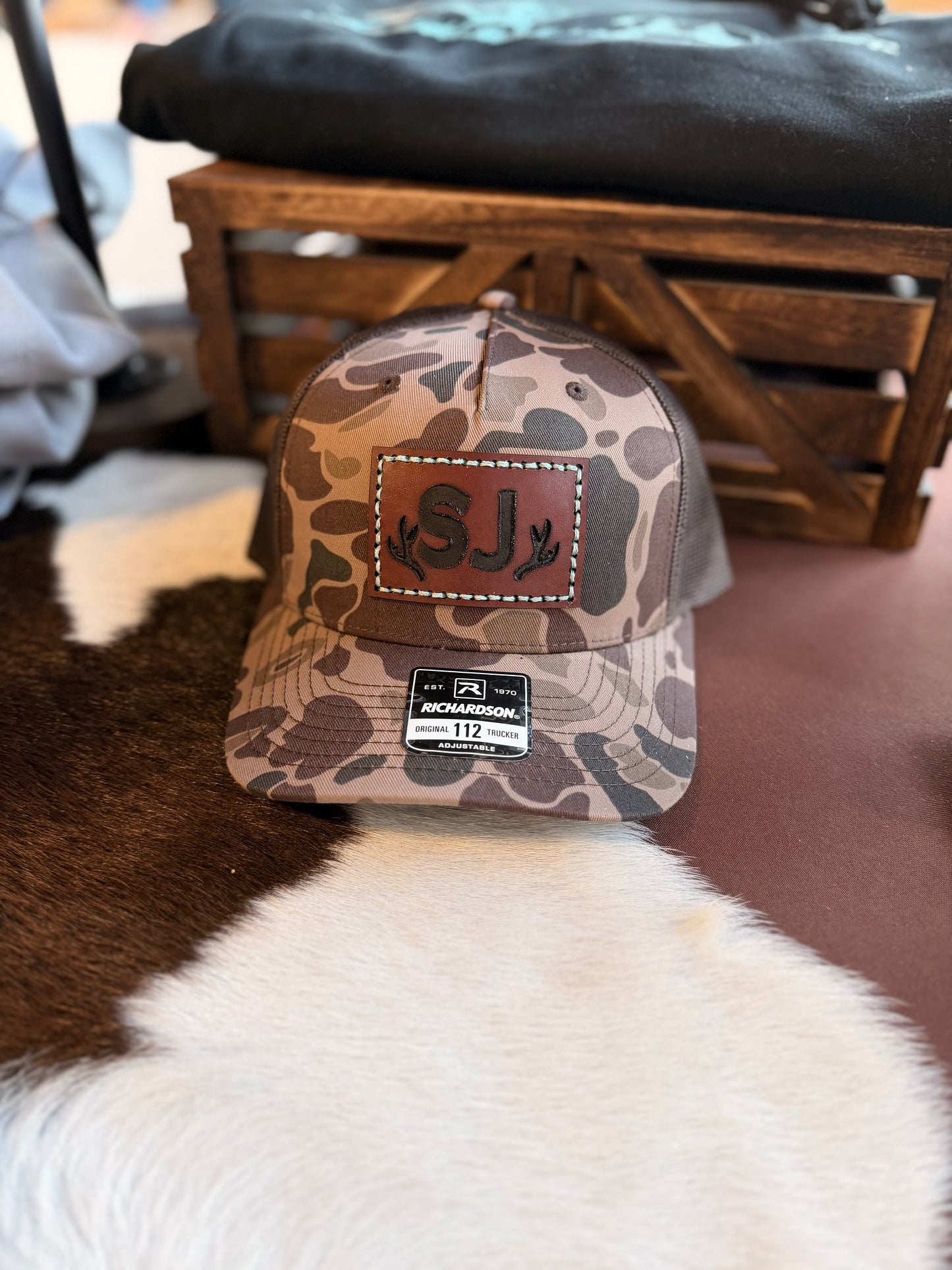 Brown Duck Camouflage baseball cap with custom branded leather patch and Richardson logo with a wooden background.