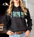 Person wearing a black hoodie with green graphic design, standing indoors.