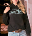 Person wearing a black hoodie with a graphic design, standing indoors.