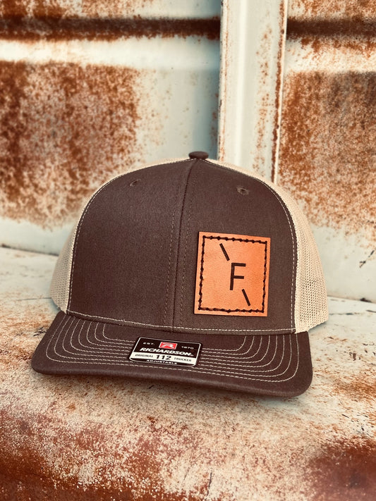 Brown trucker cap with leather patch on a rustic metal surface