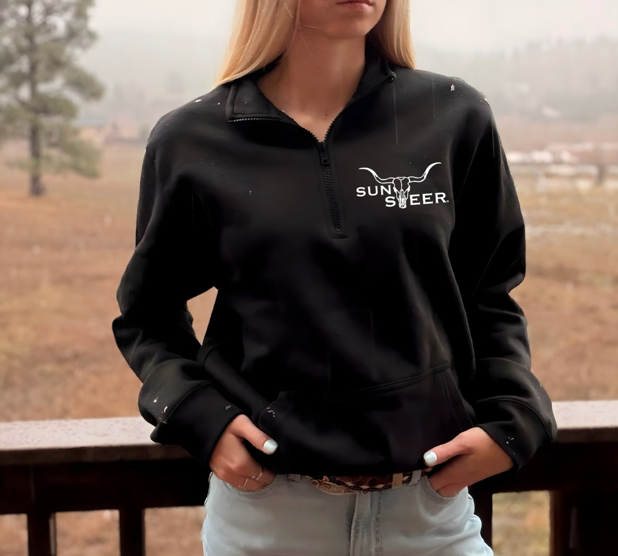 Person wearing a black sweatshirt with 'Sunrise Deer' logo outdoors.