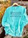 Turquoise sweatshirt with 'the devil can scrap but the lord has won' text with a dessert scene on a wooden surface