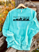 Mint sweatshirt with a proverbs 27:23 verse and cowboy graphics on a wooden surface
