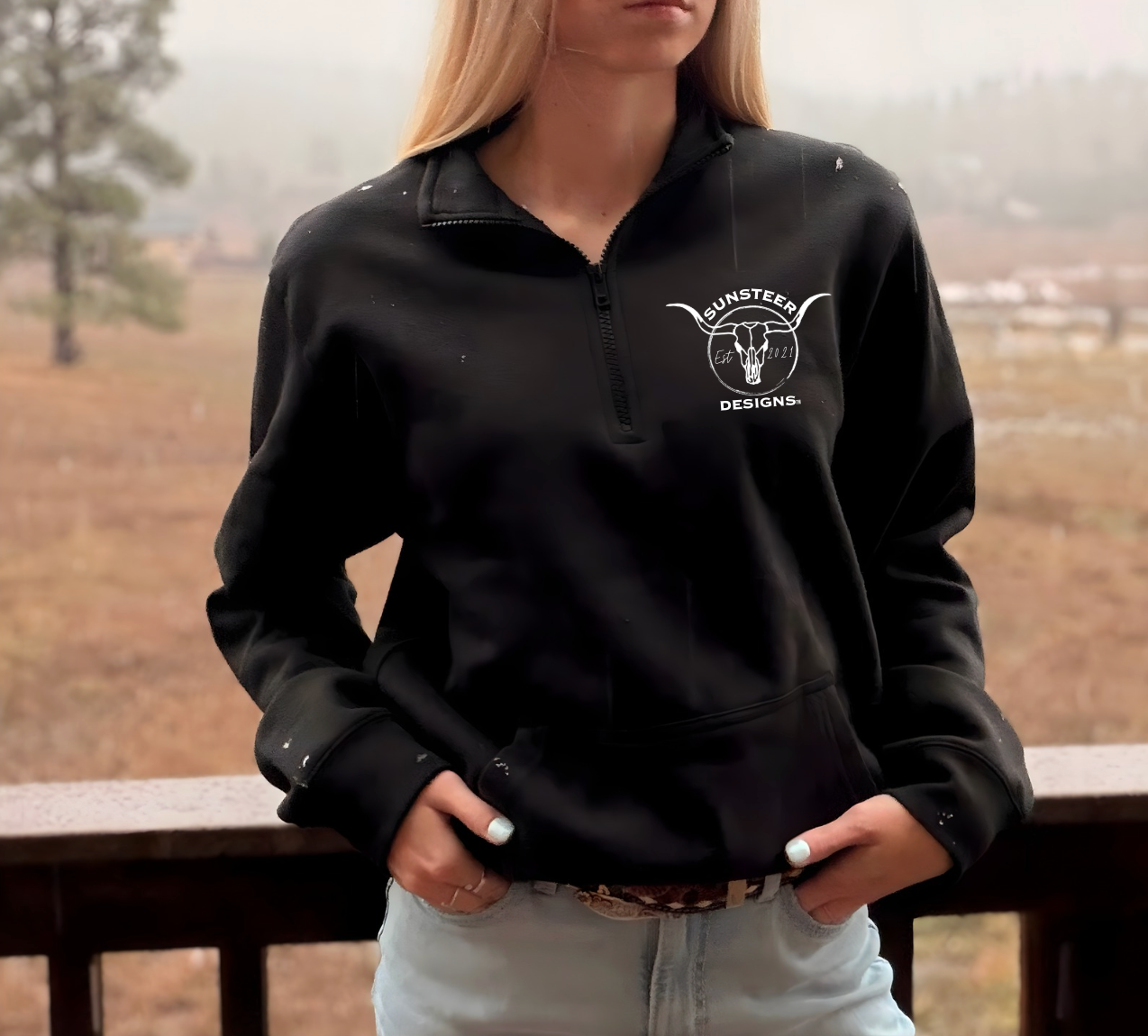 Person wearing a black pullover with a logo, standing outdoors on a foggy day.