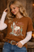 Woman wearing a brown Valentine's Day shirt with a horse graphic, standing against a wooden background.